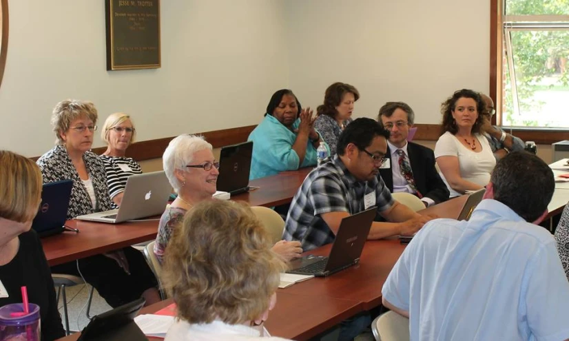 a group of people sitting at tables in front of laptops