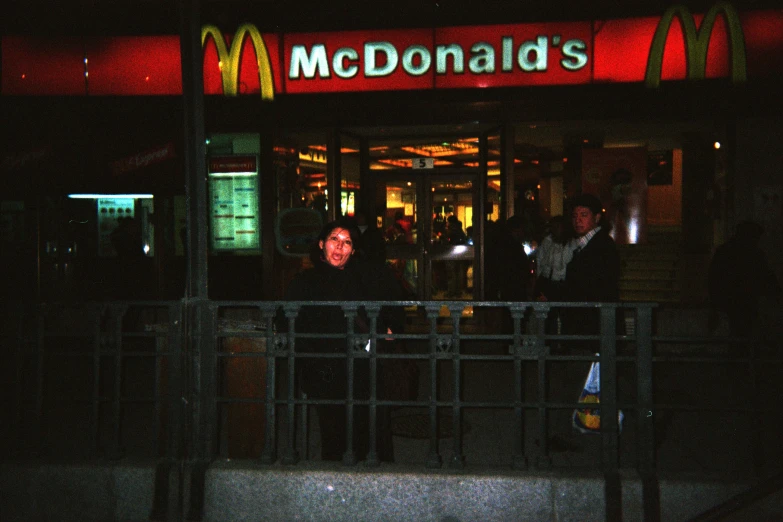 people walk by the front of a restaurant called mcdonalds