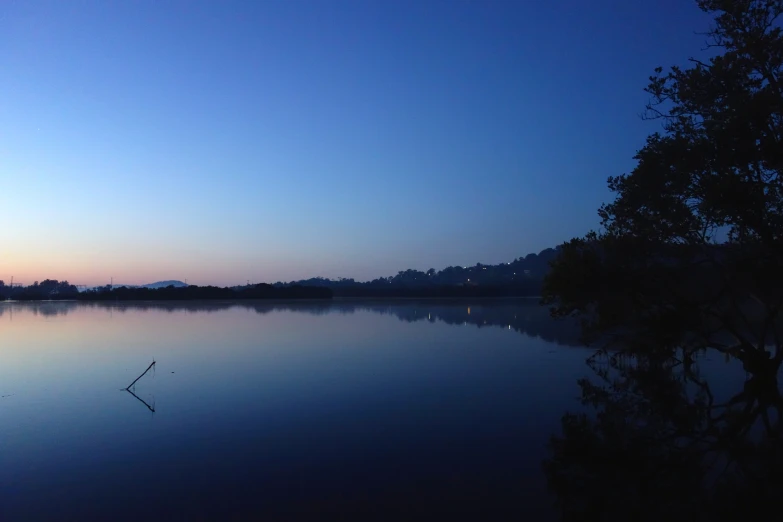 a calm lake with trees in it at sunset