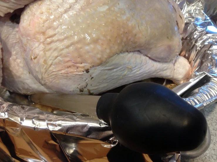 chicken being prepared in aluminum foil with a large scoop