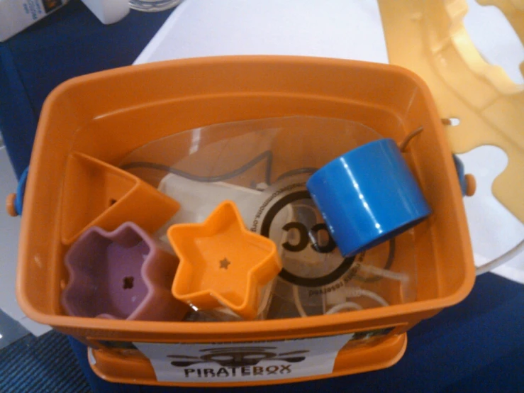 an orange box with scissors and other objects in it