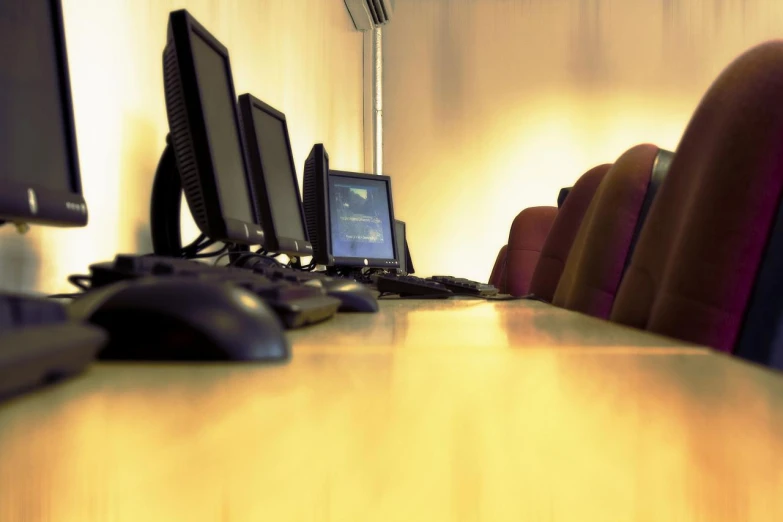 a desk with multiple computers on it and chairs