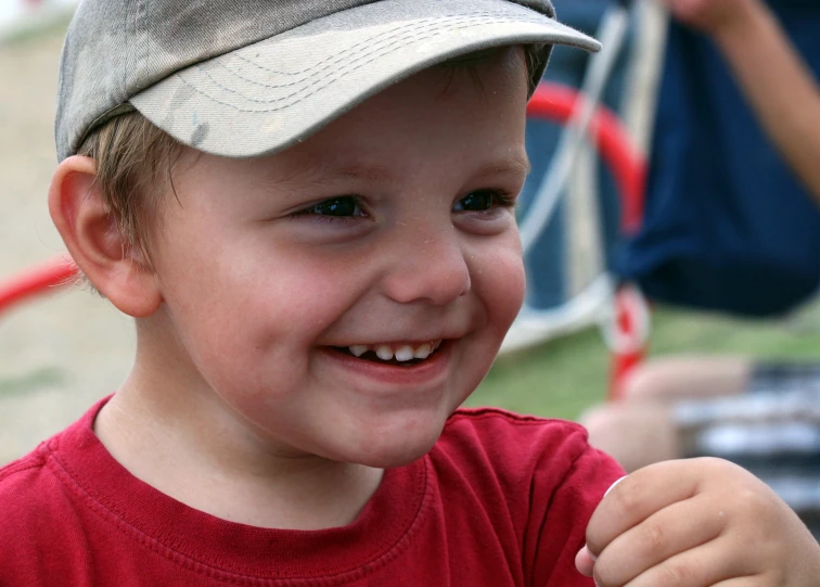 a smiling boy in red and grey has one eye on the camera