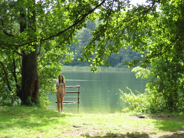woman at edge of water, by wooden bench with railing in foreground