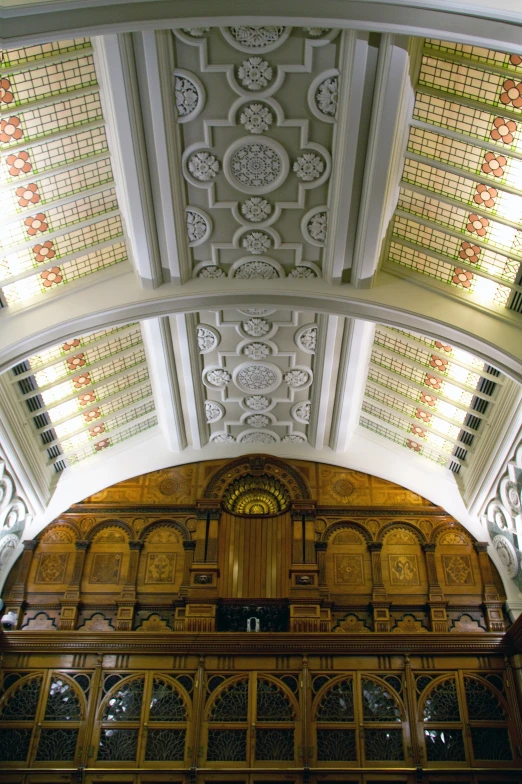 ceiling with ornate decorations and arched windows with sun coming in