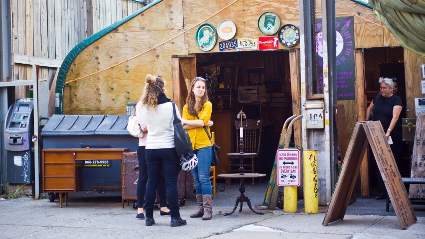 women outside of a store next to wooden planks