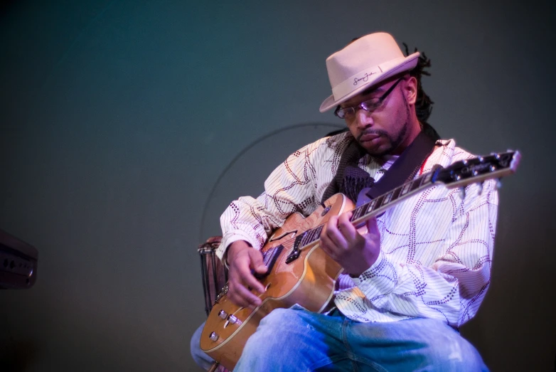 a man in a hat playing on an acoustic guitar