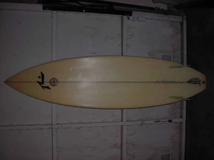 a white surfboard sitting against a brick wall