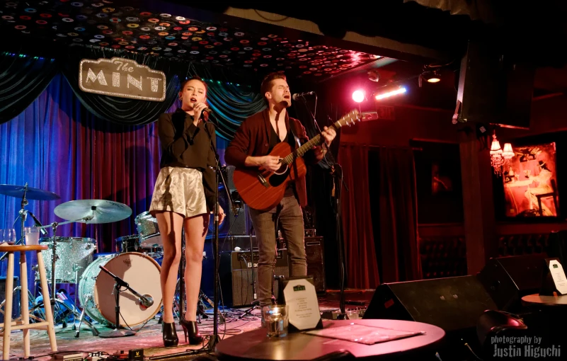 man and woman singing with an acoustic instrument and a guitar