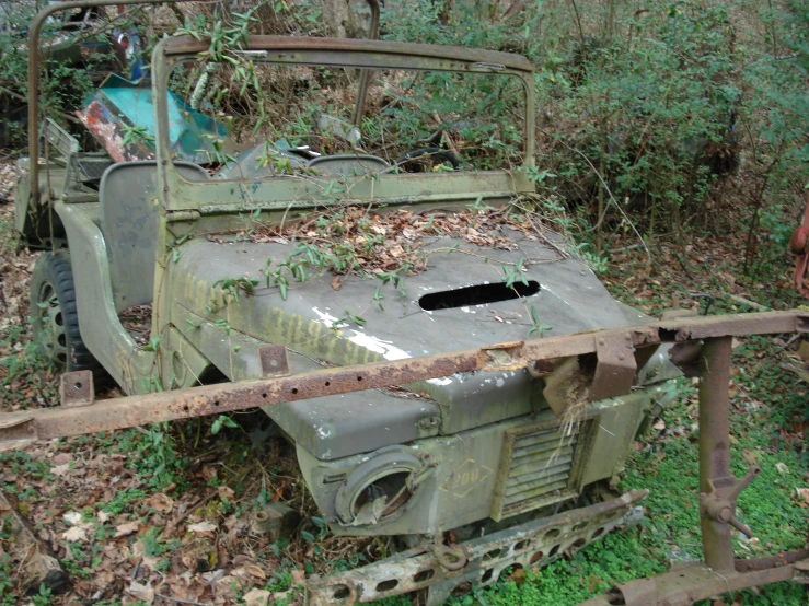 an old military jeep sitting on top of leaves