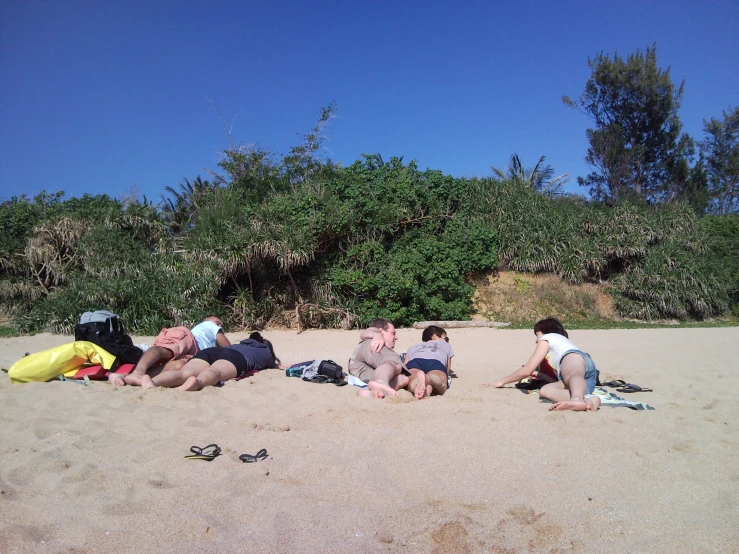 three people laying on a beach with backpacks and water sports gear