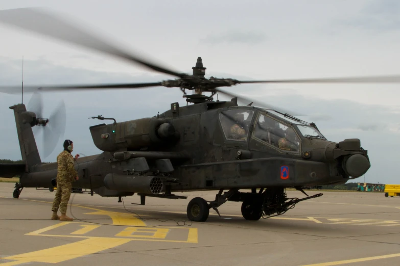 two men stand in front of a black helicopter