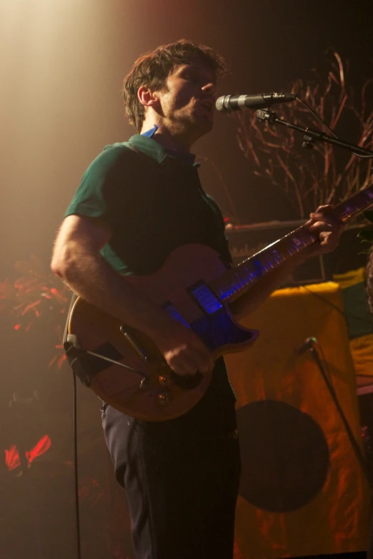 a male with a guitar sings into a microphone