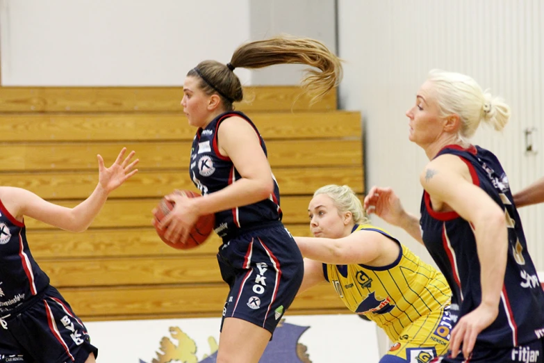 girls in blue uniforms playing basketball against each other