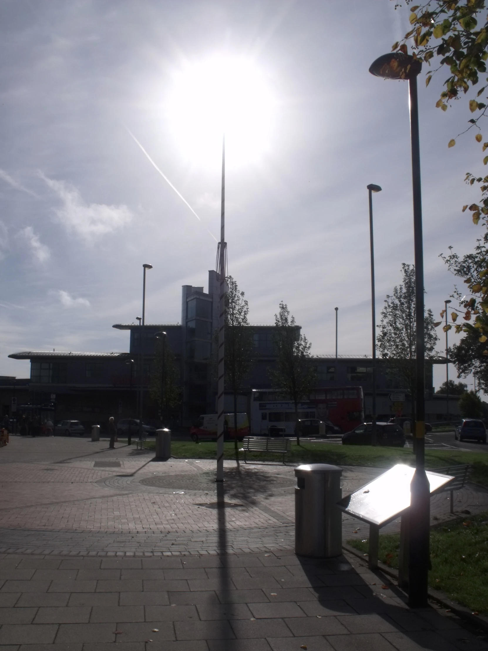 a square in front of an industrial building with a bench next to it