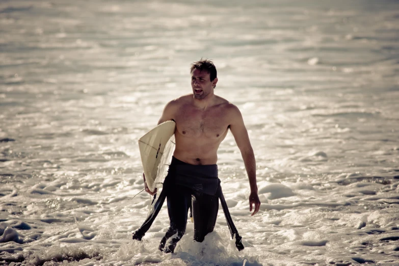 there is a man walking through the ocean with a surfboard