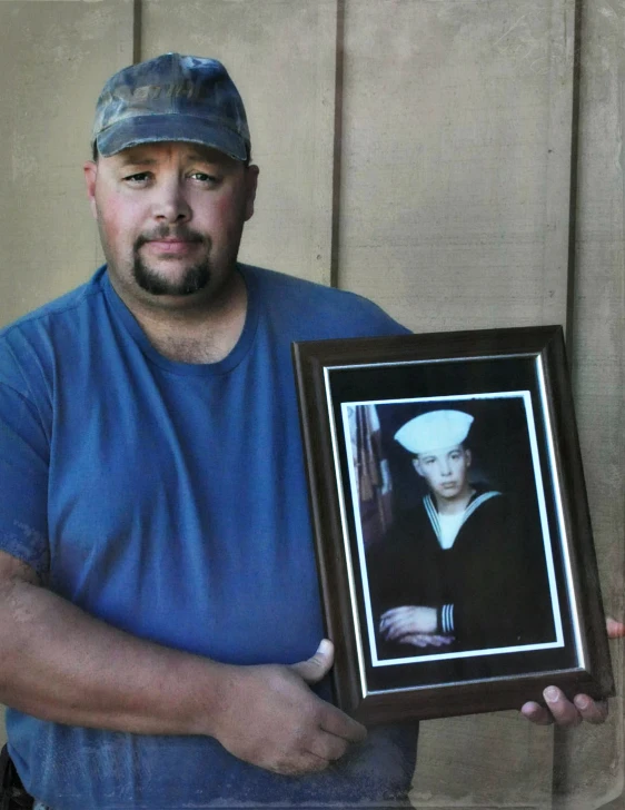 a man holding up a framed pograph of an old man