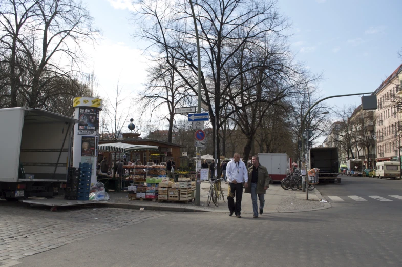 two men walking down the street by some buildings