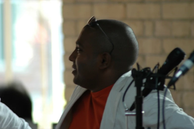 a bald man with a large headphones standing next to microphone