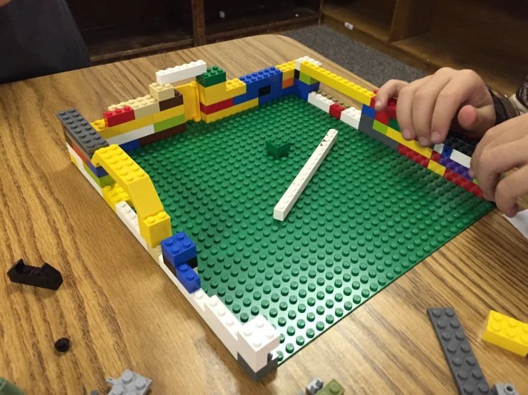 a child holds their hand over a lego soccer field