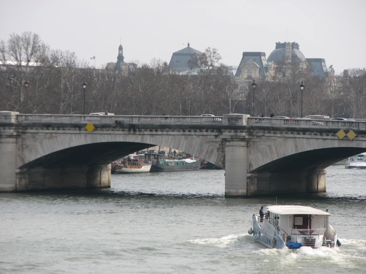 boat moving under bridge that is connected to buildings