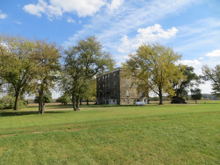 a field with lots of trees and a big building in the background