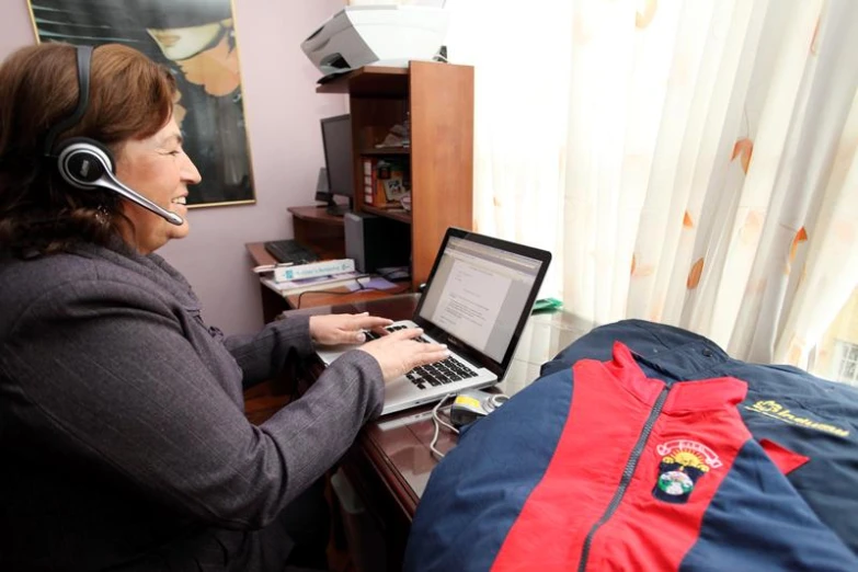 a woman sitting in a room working on a laptop