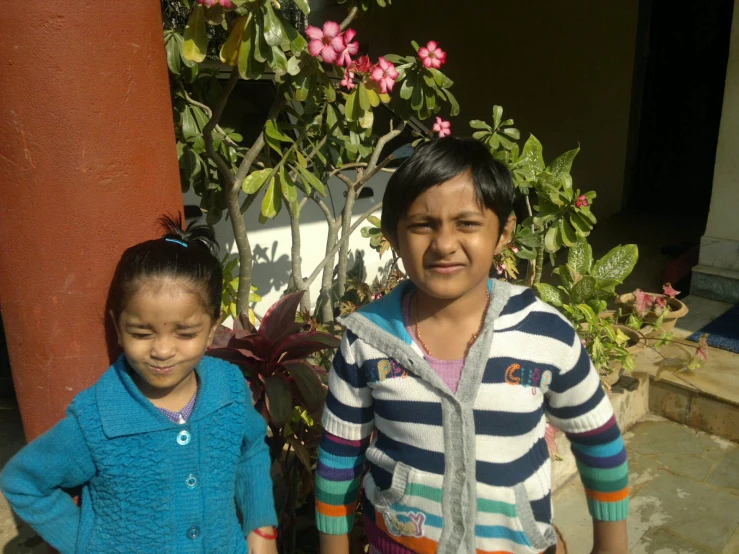 two s standing in front of a plant