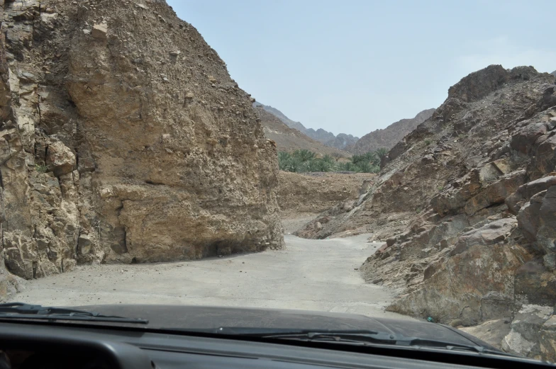 a car is driving around a rocky, narrow hill