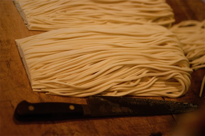 a wooden  board covered with cooked spaghetti