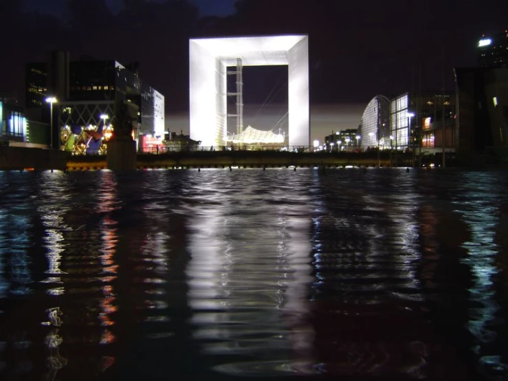 a city skyline at night with the reflecting lights of a building and its surroundings