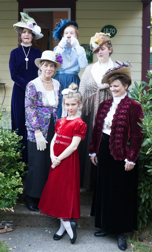 a group of women are posing outside in dress