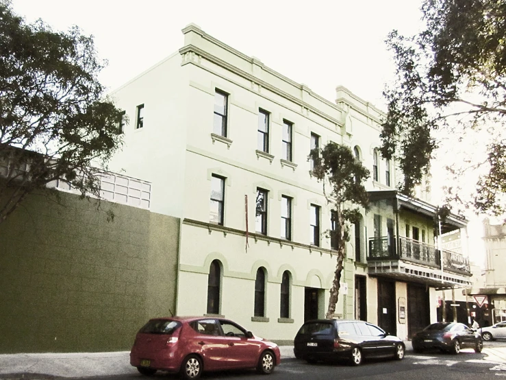 this city street has a white building and cars parked on the side