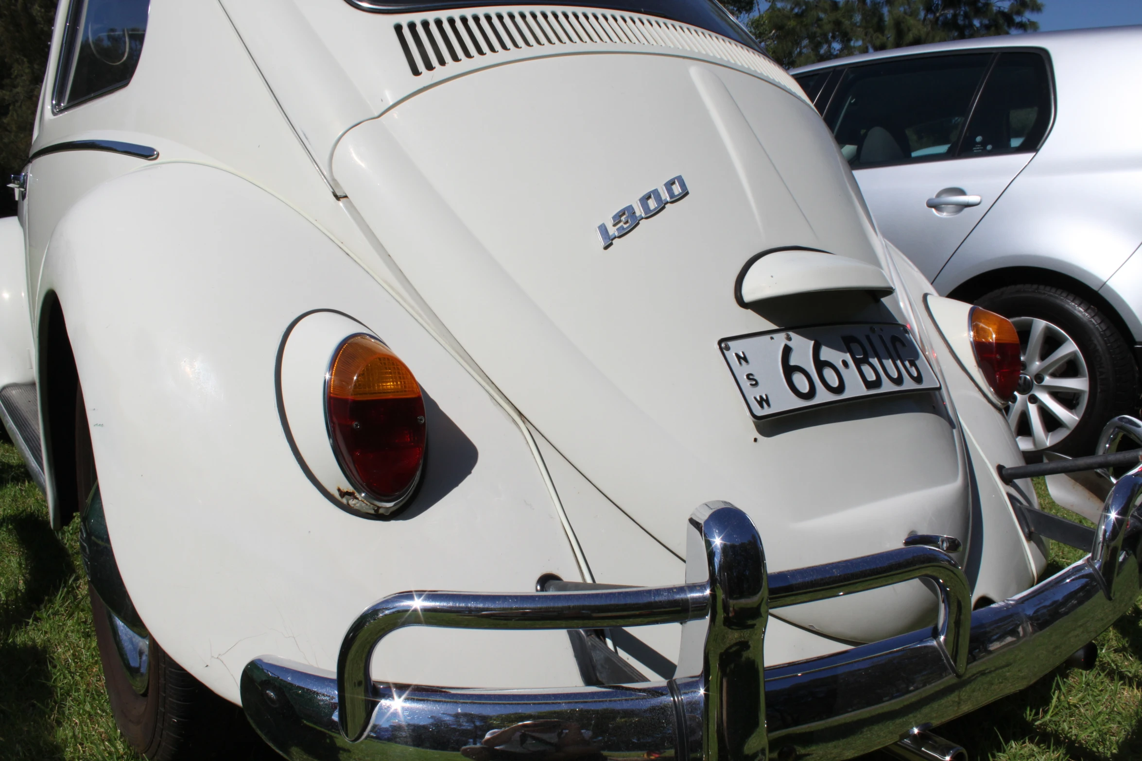 a white beetle is parked in the grass