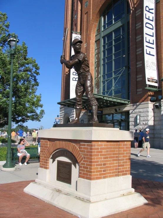 the bronze statue is at the base of a baseball monument