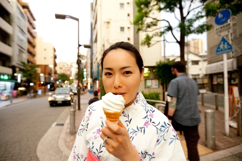 a woman stands on the sidewalk holding an ice cream cone