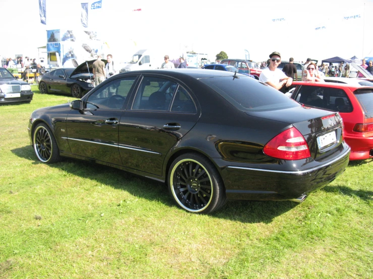 there is a black mercedes with some rims parked on the grass