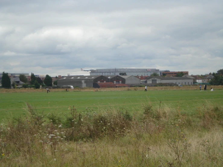 several people playing in a large field with a building in the background