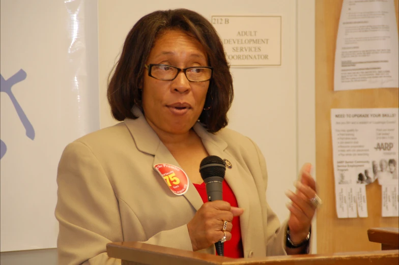 a woman speaking into a microphone with a on around her neck