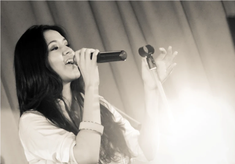 a woman in a white shirt singing into a microphone