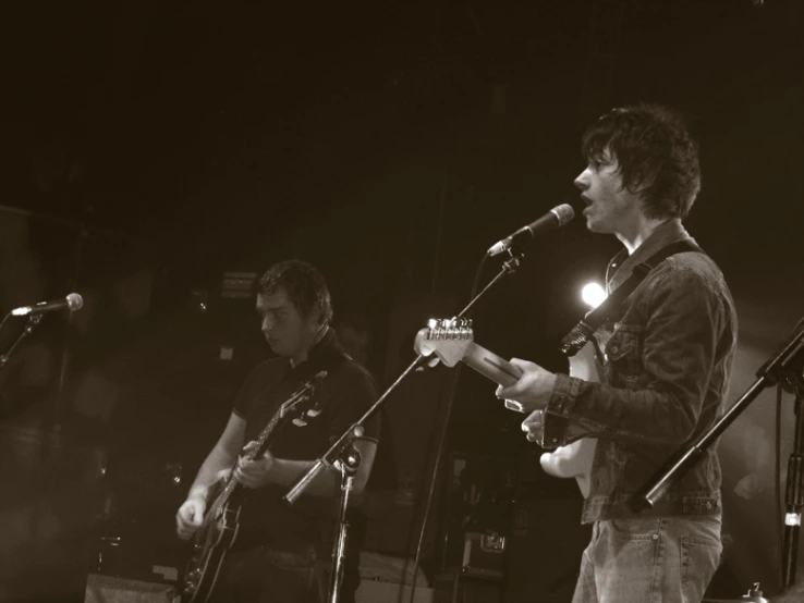 two guys on stage playing musical instruments at night