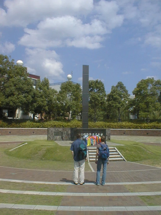 two people looking into a well - maintained park with a sculpture in the background