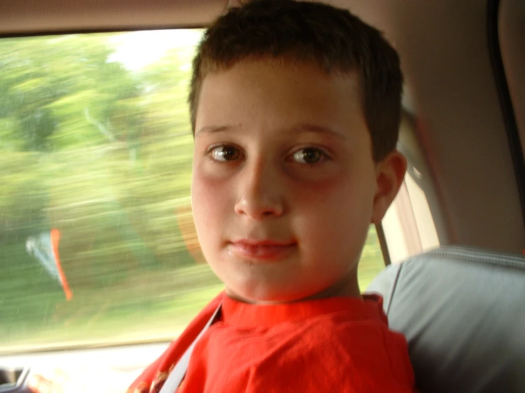 a little boy in a car seat is staring at the camera