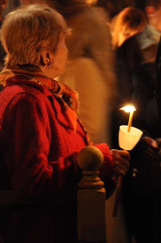 there is a lady holding a small candle in her hand