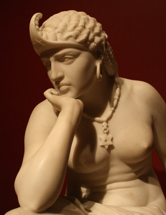 a statue of a person sitting wearing a necklace