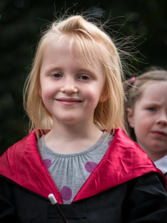 a girl in a red cape is smiling