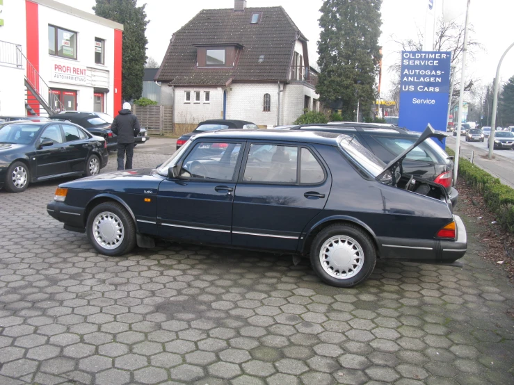 a blue car sits outside with the open door on the side