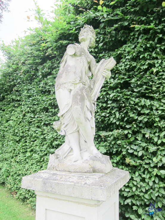 a statue of a woman is near green hedges