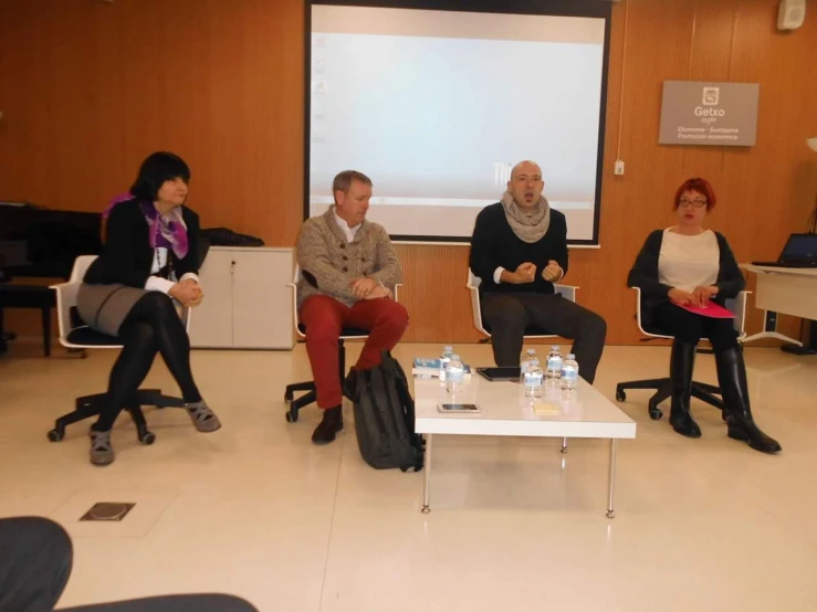 four people sitting in a conference room during a presentation