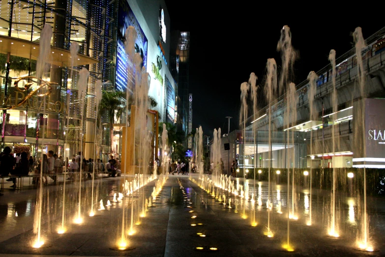 a lighted water fountain in the middle of a street